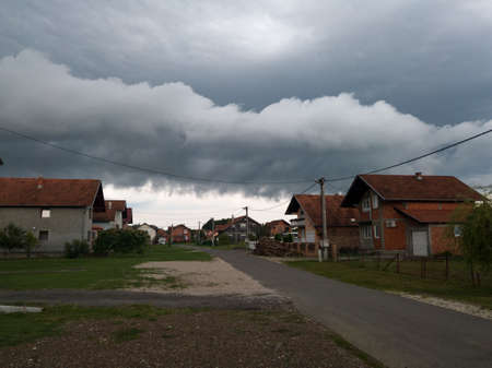 Dangerous dramatic dark clouds above settlement, ominous stormy weather with rain during summerのeditorial素材