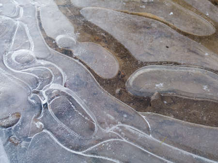 Round irregular shapes in ice on frozen puddle in winter, concept of rigidity and stillness
