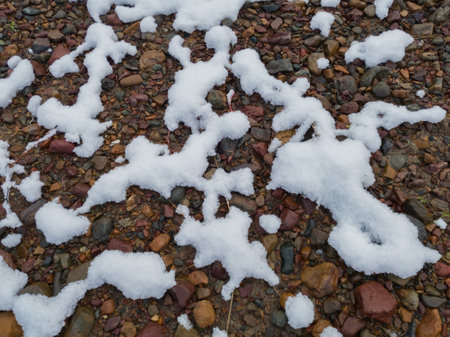 Snow pattern on wet gravel terrain, snow meltingの写真素材