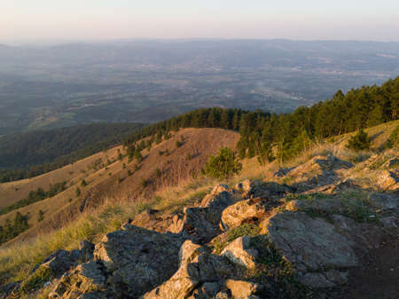 View from the top of Gostilj on the mountain Ozren on the slopes and villages in the valley, a landscape of hilly Balkans with haze on the horizon at eveningの写真素材
