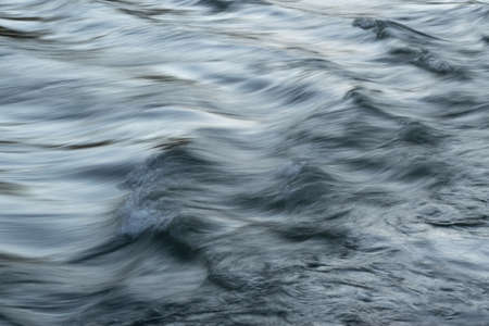 Rapid water flow in mountain stream with silky surface and motion blur - abstract landscape close upの写真素材