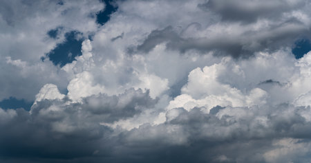 Big bright clouds against dark blue sky, cloud in dramatic light, panoramic viewの写真素材
