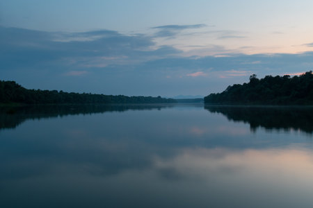 Landscape of cloudy twilight with symmetric reflection on water surface, distant mountain in hazeの写真素材