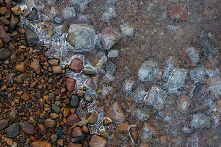 Frozen puddle on gravel, ice texture with air bubblesの写真素材