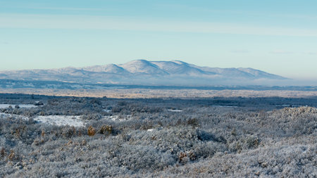Village at dawn with distant mountain in sunlight, wintry landscapeの写真素材