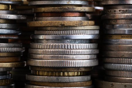 Edges of various coins stacked in piles close up, reeded and decorated, uncirculated metal money with scratches, dents and corrosion damageの写真素材
