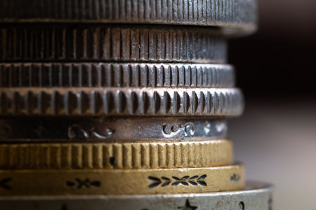 Edges of various coins stacked in pile close up, reeded and decorated, uncirculated metal money with scratches and corrosion damageの写真素材