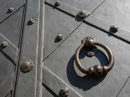 Detail of an old iron door with a brass knocker.の写真素材