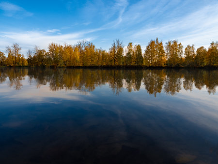 A beautiful view of a lake in Poland, with a strip of trees in the distance, covered in fall colors.の写真素材