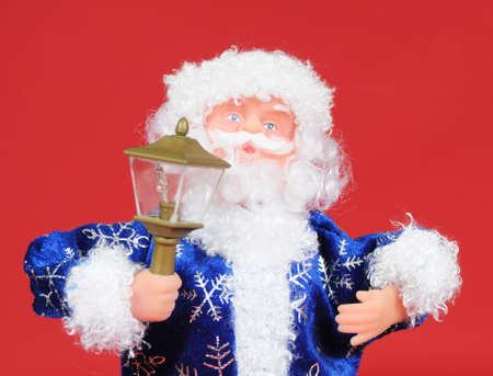 Toy santa claus with a lantern on red backgroundの写真素材
