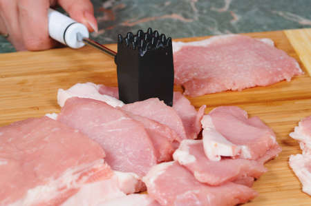 The cook prepares a chop from porkの写真素材