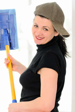A smiling woman in a cap washes a windowの写真素材