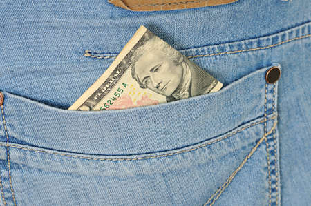 Ten dollars stick out of a pocket of  blue jeans