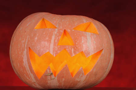 pumpkin with lighting candle inside on red backgroundの写真素材