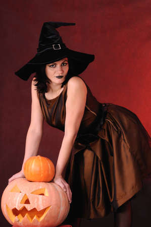 Young witch with a pumpkin on a black  backgroundの写真素材