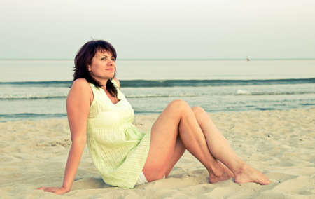 The woman sits on a beach in the eveningの写真素材
