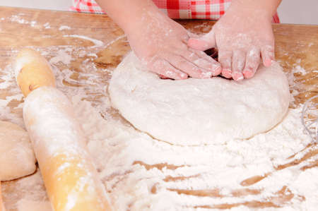 a little girl is cooking the dough for making biscuits