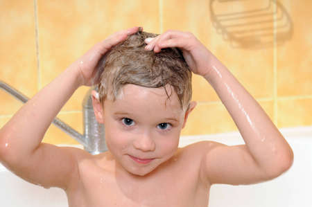 child washing in the shower with a foam on the head の写真素材