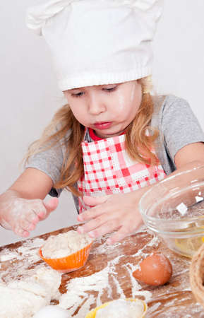 girl in chef's hat cooking dough for cakeの写真素材