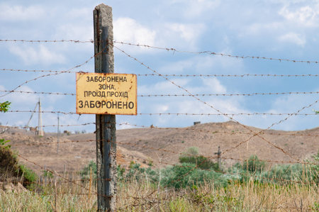 pillar with a prohibition sign and barbed wire fenceの写真素材