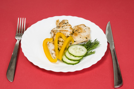 grilled chicken fillet on a white plate and red backgroundの写真素材