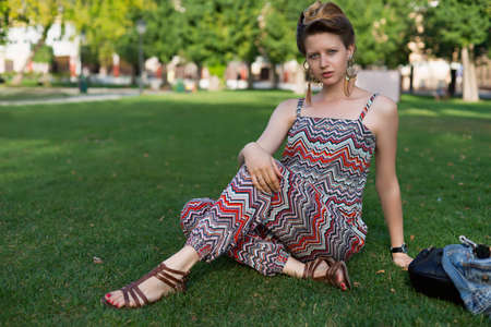 Pregnant woman lying on green grass outdoors. Model summer look. Having fun. Motherhood. Maternity.の写真素材