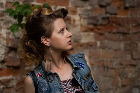 Beautiful pregnant woman wearing long dress and jean jackets standing at a textured bricks wallの写真素材