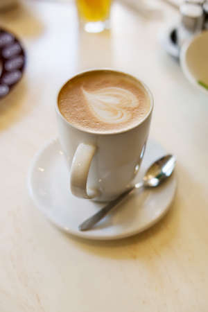 Extra large cappuccino cup with spoon on the brown wooden tableの写真素材