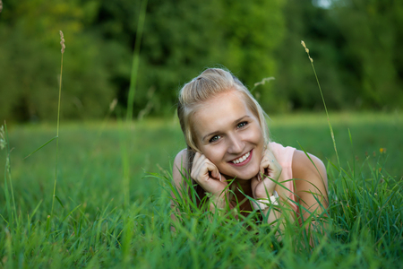 A happy laughing young woman laying on the grass and looking into the camera.の写真素材