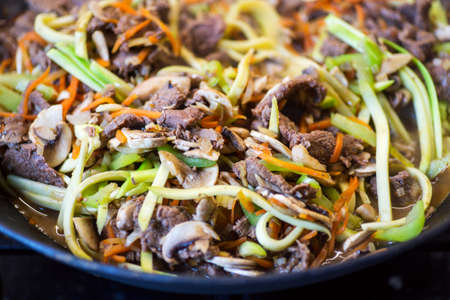 Noodles with pepper, carrot, mushrooms, zucchini and meat on wok.の写真素材