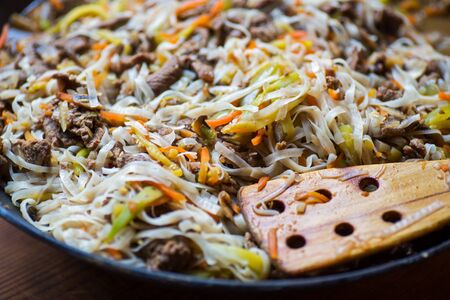 Traditional asian beef meat with vegetables in wok and wooden spatulaの写真素材