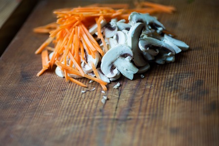 Sliced champignon mushrooms and carrote on a wooden deck.の写真素材