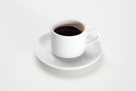 Black coffee with bubbles in white cup with saucer.の写真素材