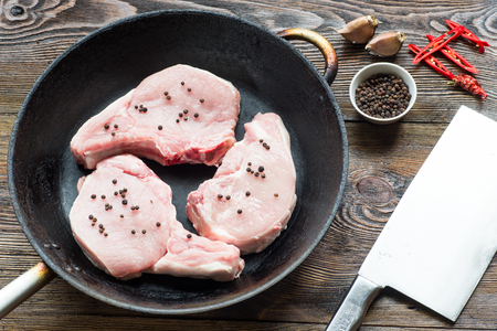 Raw Pork Loin Steaks in a dish on wooden table. Ready for fryの写真素材