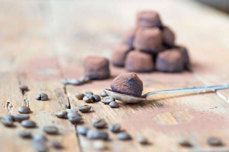 Dark chocolate truffles with cocoa powder, coconut and chopped hazelnuts on a wooden table.の写真素材