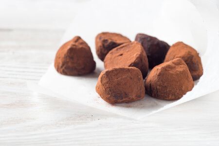 Chocolate truffle candies in the paper packing on the white wooden table horizontal