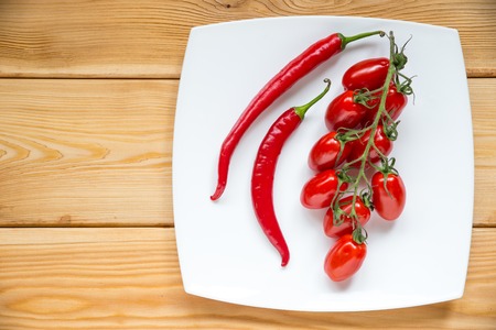 Top view of cherry tomatos, chilly pepper on wood background with copyspace.の写真素材