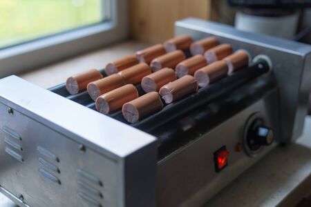 The grilled sausages roll on heating machine. Hot dogs on Roller Grill.の写真素材