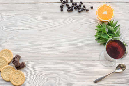 Top view of fruit tea on wooden plank table, chocolate, mint, orange, cookies, raisins in chocolateの写真素材