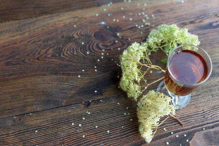 Glass of herbal tea and linden and Melissa flowers, bright wooden table, high angle view