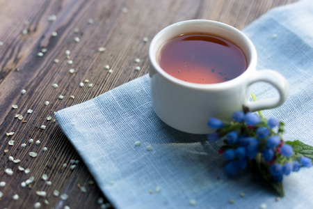 Cup of herbal tea and linden and Melissa flowers, bright wooden table, high angle viewの写真素材