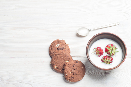 Fresh strawberries and homemade chocolate cookies on rustic white wooden table. Top view.の写真素材