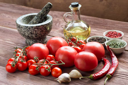 Vegetables ready to cook: tomatoes, pepper, onion, olive oil, pepper on wooden background. Fresh vegetable salad ingredients. Horizontal.の写真素材