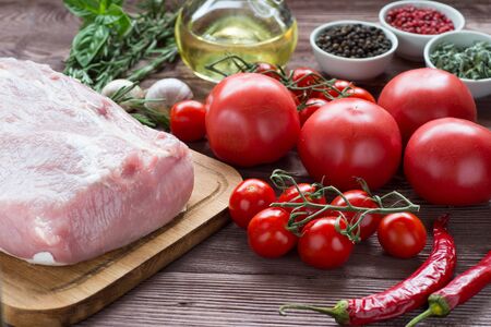 Raw pork meat on a dark wooden surface and ingredients for cooking. Food background.の写真素材