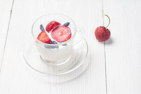 Milk fruit dessert. Serving tasty treats from dairy cream and red strawberries standing on the wooden table.の写真素材