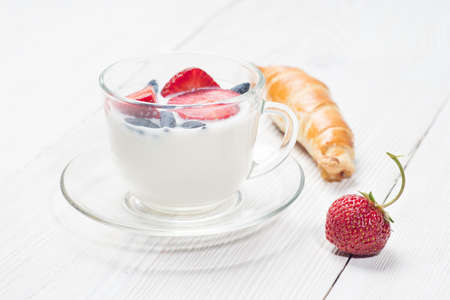 Milk fruit dessert. Serving tasty treats from dairy cream and red strawberries standing on the wooden table.の写真素材