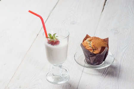 Strawberry milkshake with delicious muffin on white wooden backgroundの写真素材