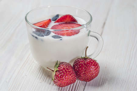 Milk fruit dessert. Serving tasty treats from dairy cream and red strawberries standing on the wooden table.の写真素材