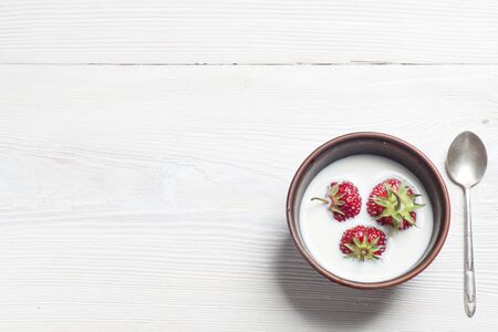 Appetizing strawberry in the bowl with spoon on rustic white wooden table, Top view.の写真素材