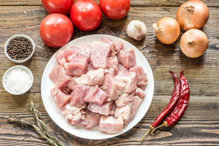Raw pork leg on wooden cutting board ready for cooking with vegetablesの写真素材